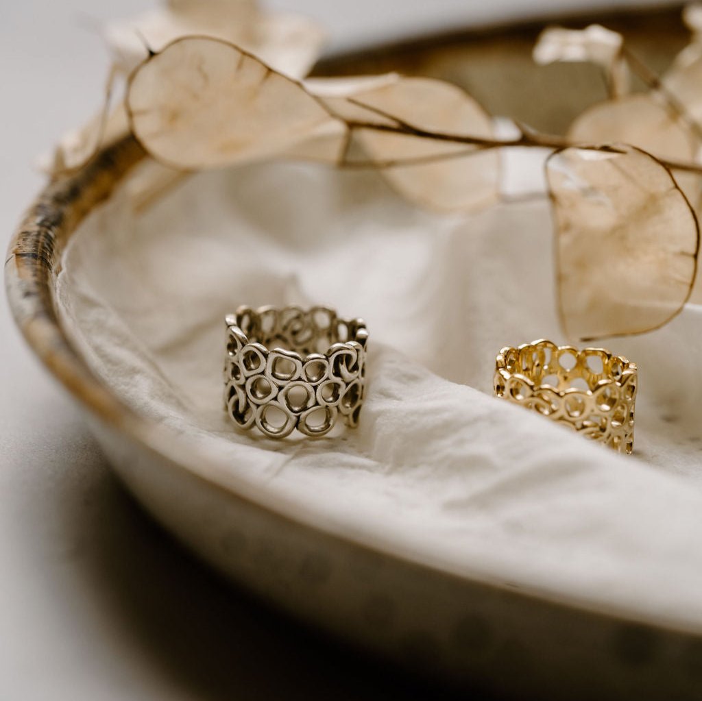 Gold & silver rings sitting on a white cloth with white flowers.
