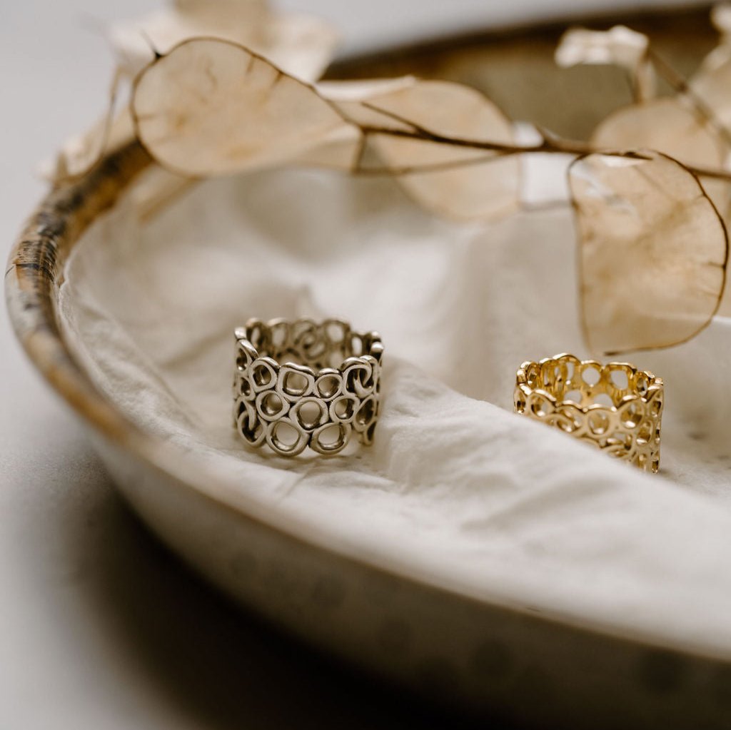 Gold & silver rings sitting on a white cloth with white flowers. 