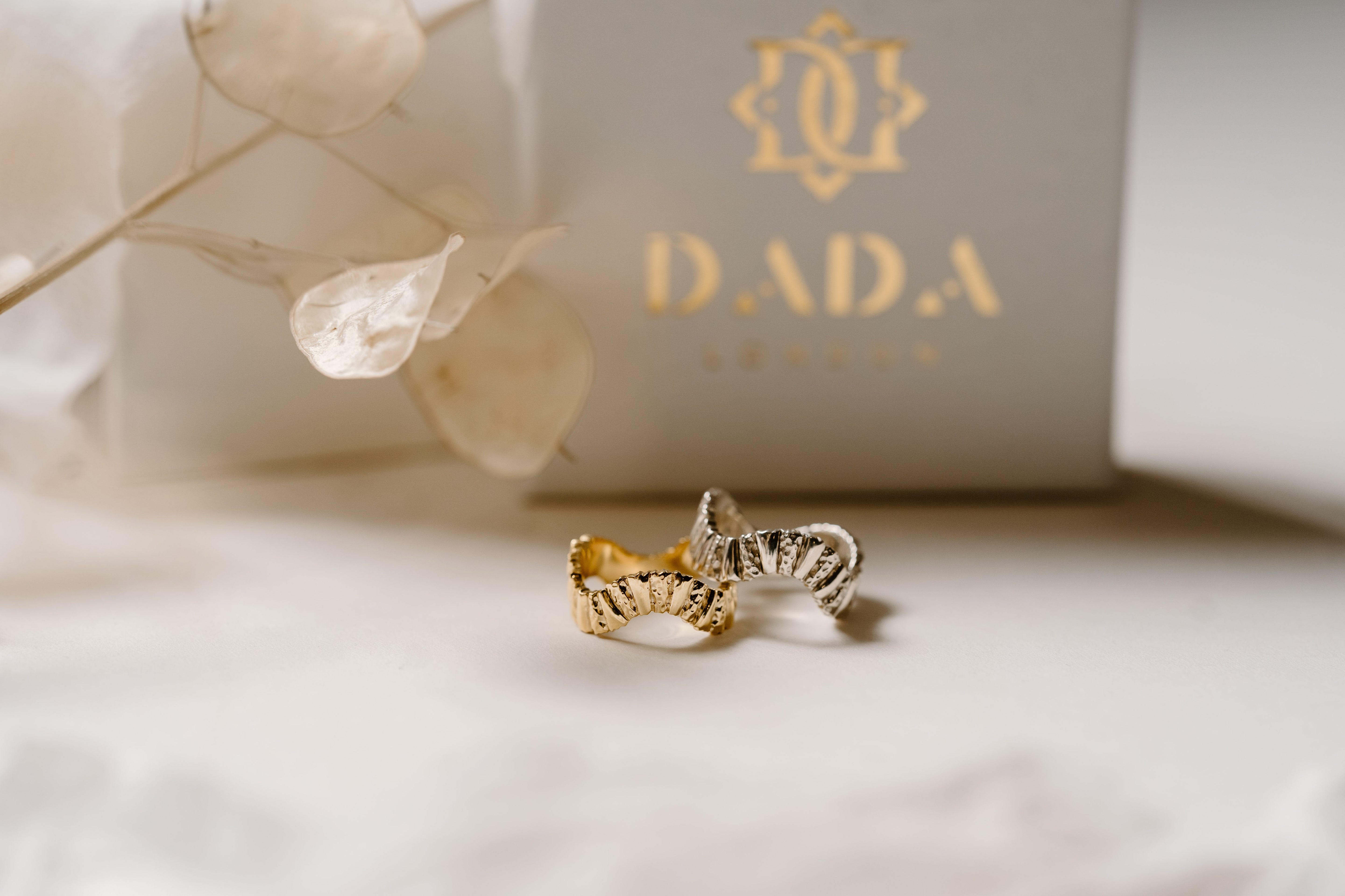 Unique silver and gold ring, in front of sustainable packaging.