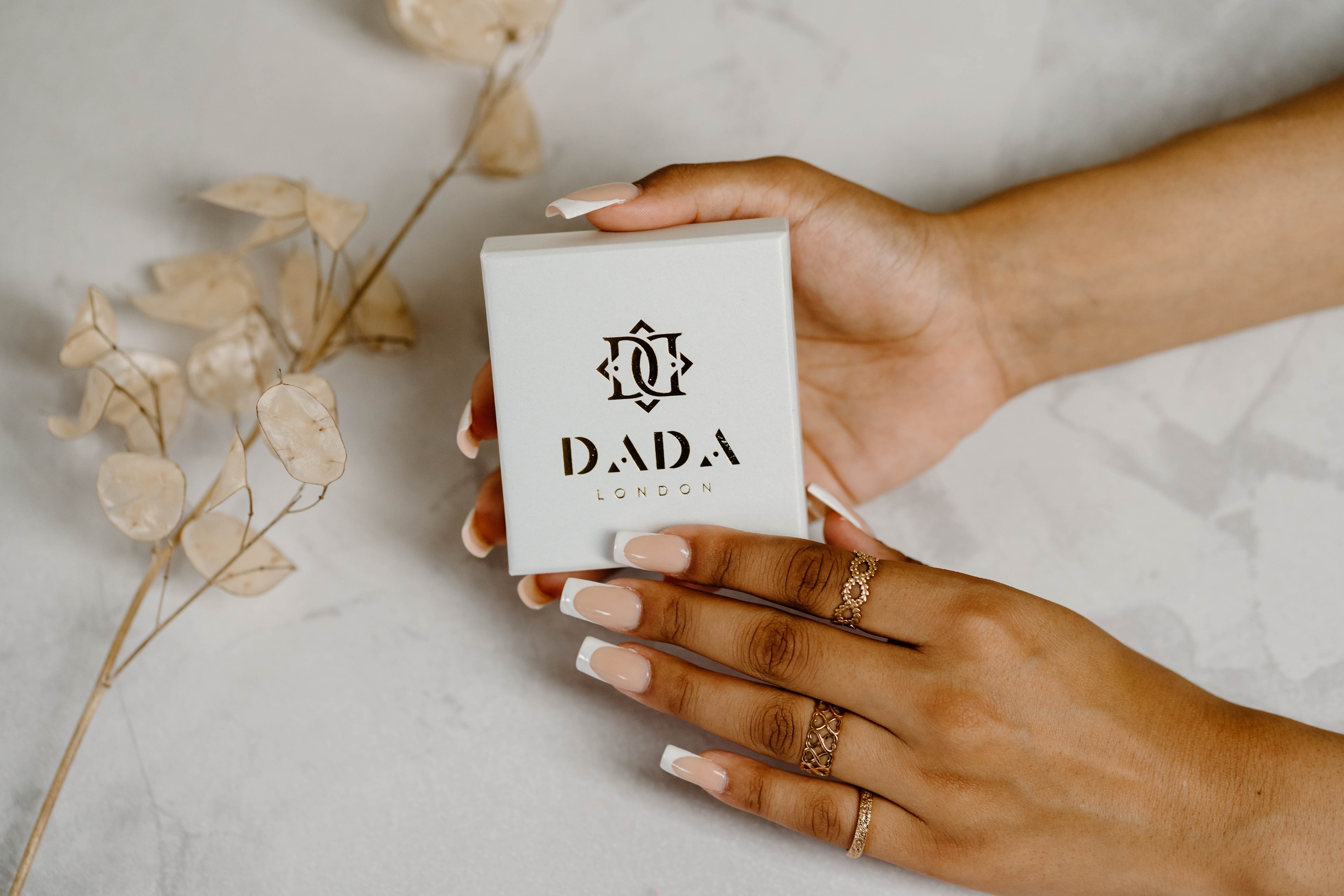 Soft, delicate hands holding jewellery packaging whilst wearing love rings.