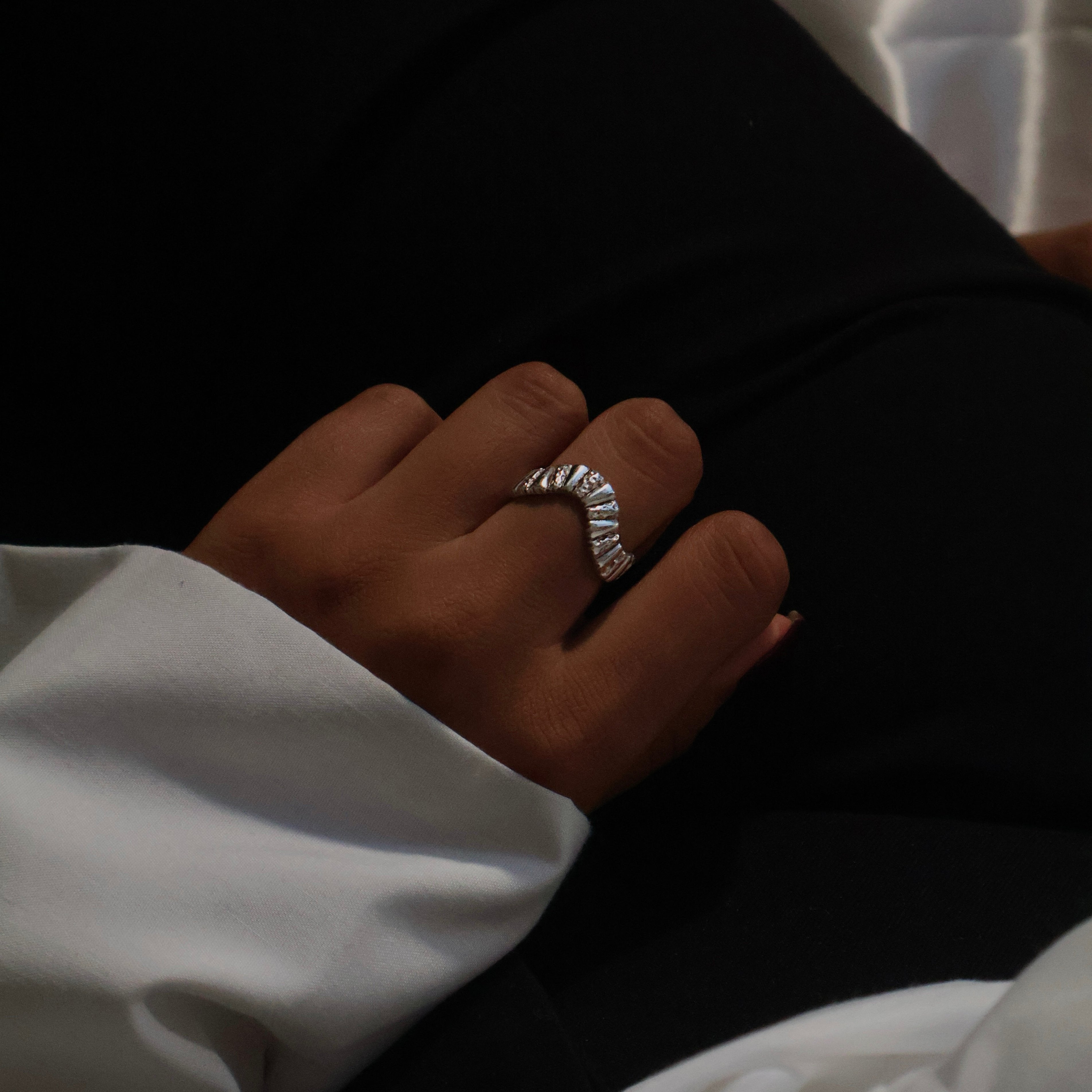 Unique silver ring, resting on women's thigh.