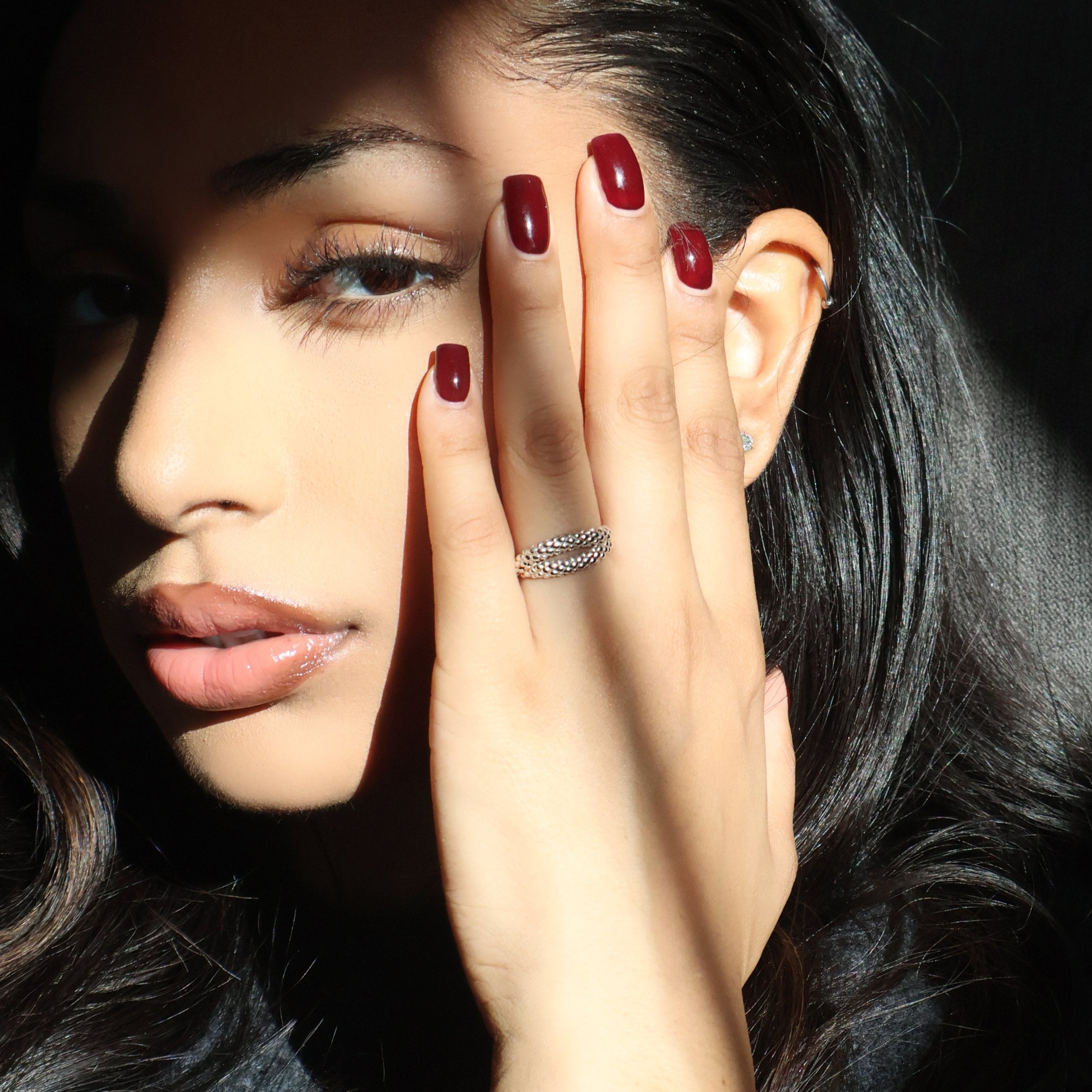 Snake ring on hand with red nails.