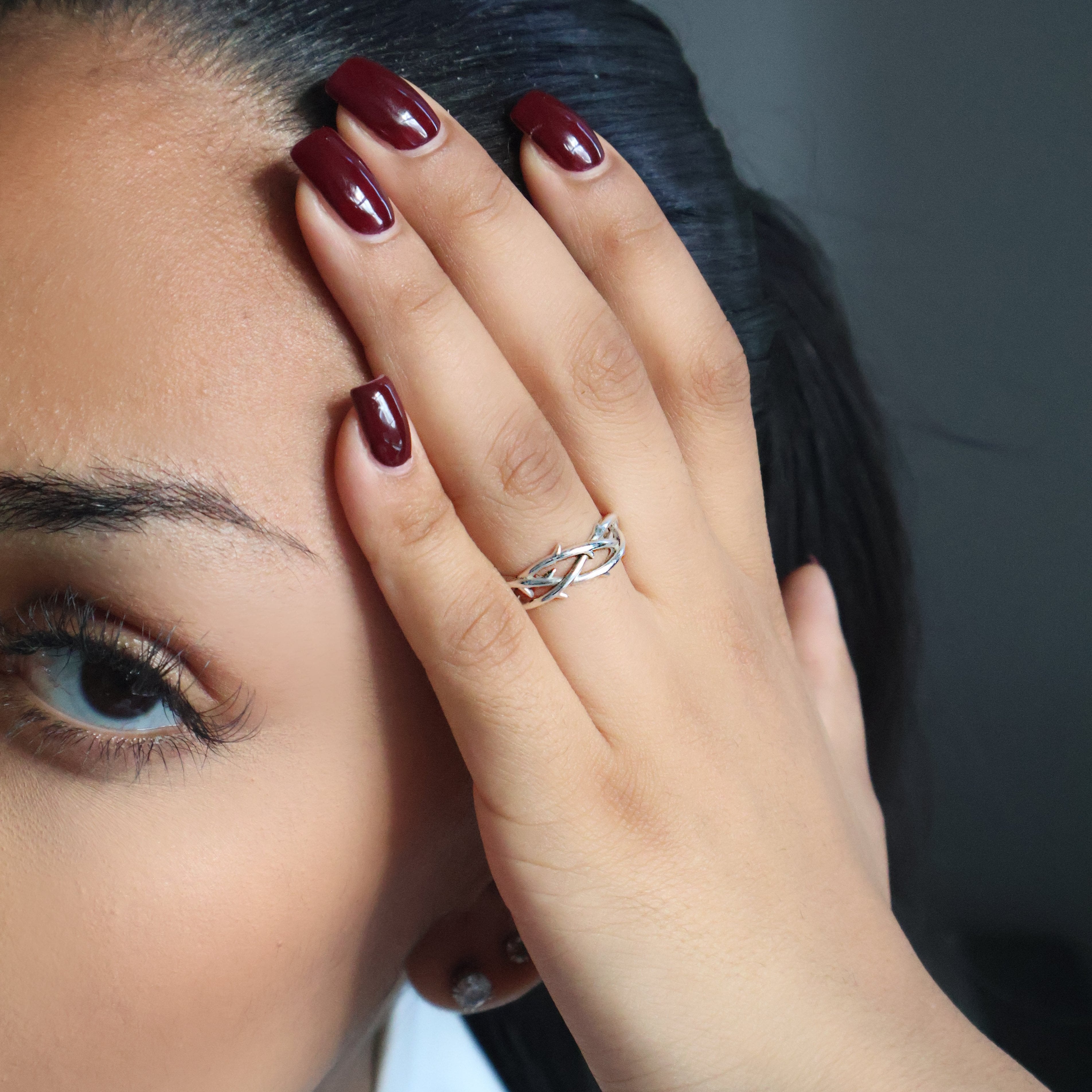 Thorn ring on women index finger, with red nails. 